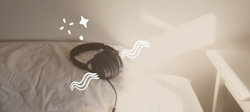 Black pair of headphones on a white bed